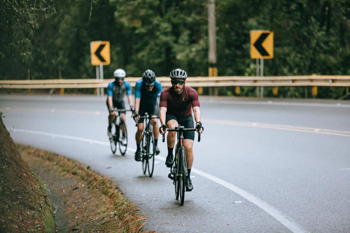 Three cyclists racing on the side of a winding road.